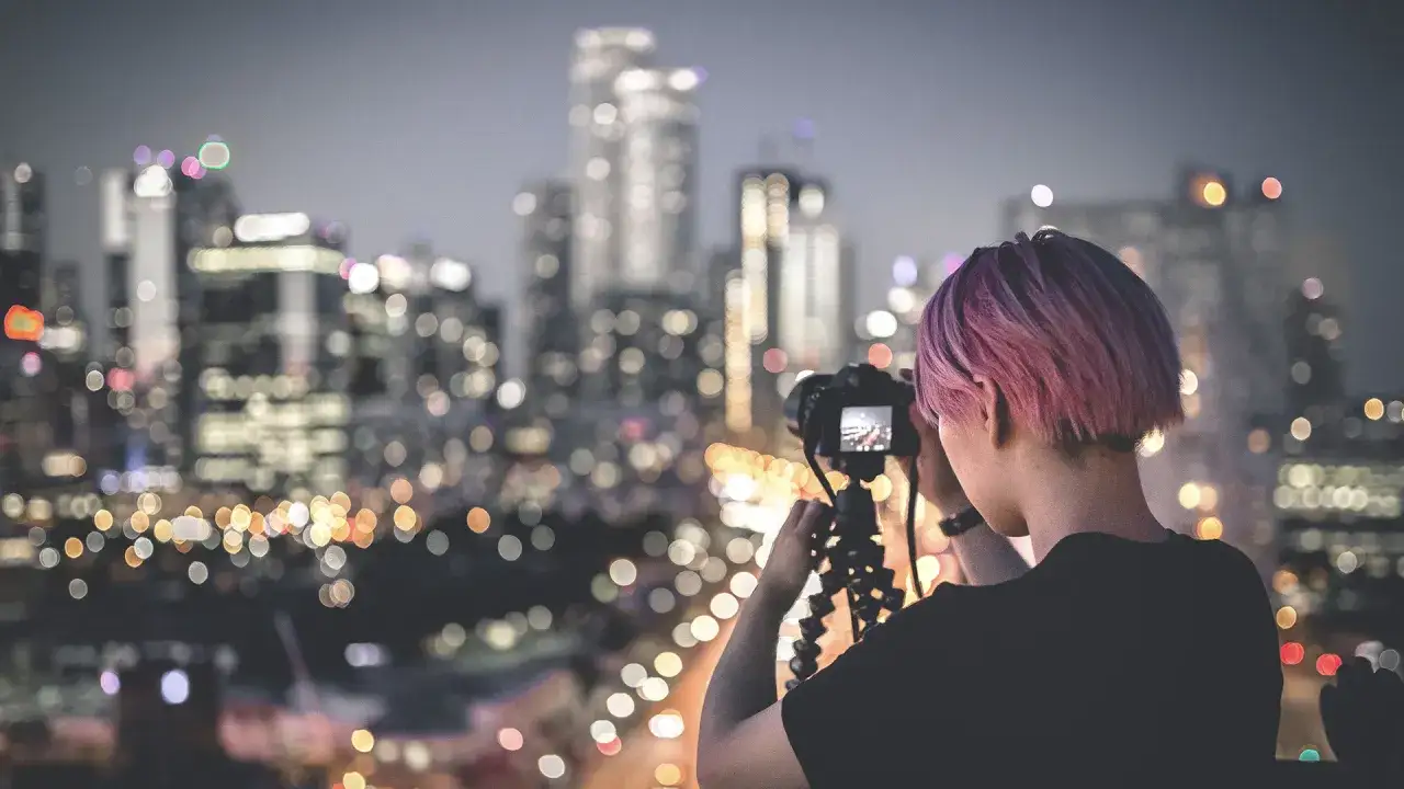 Federica Valabrega, con i capelli rosa, cattura la magia notturna di una citt&agrave; illuminata, con i suoi bokeh sfocati che creano un'atmosfera incantevole.