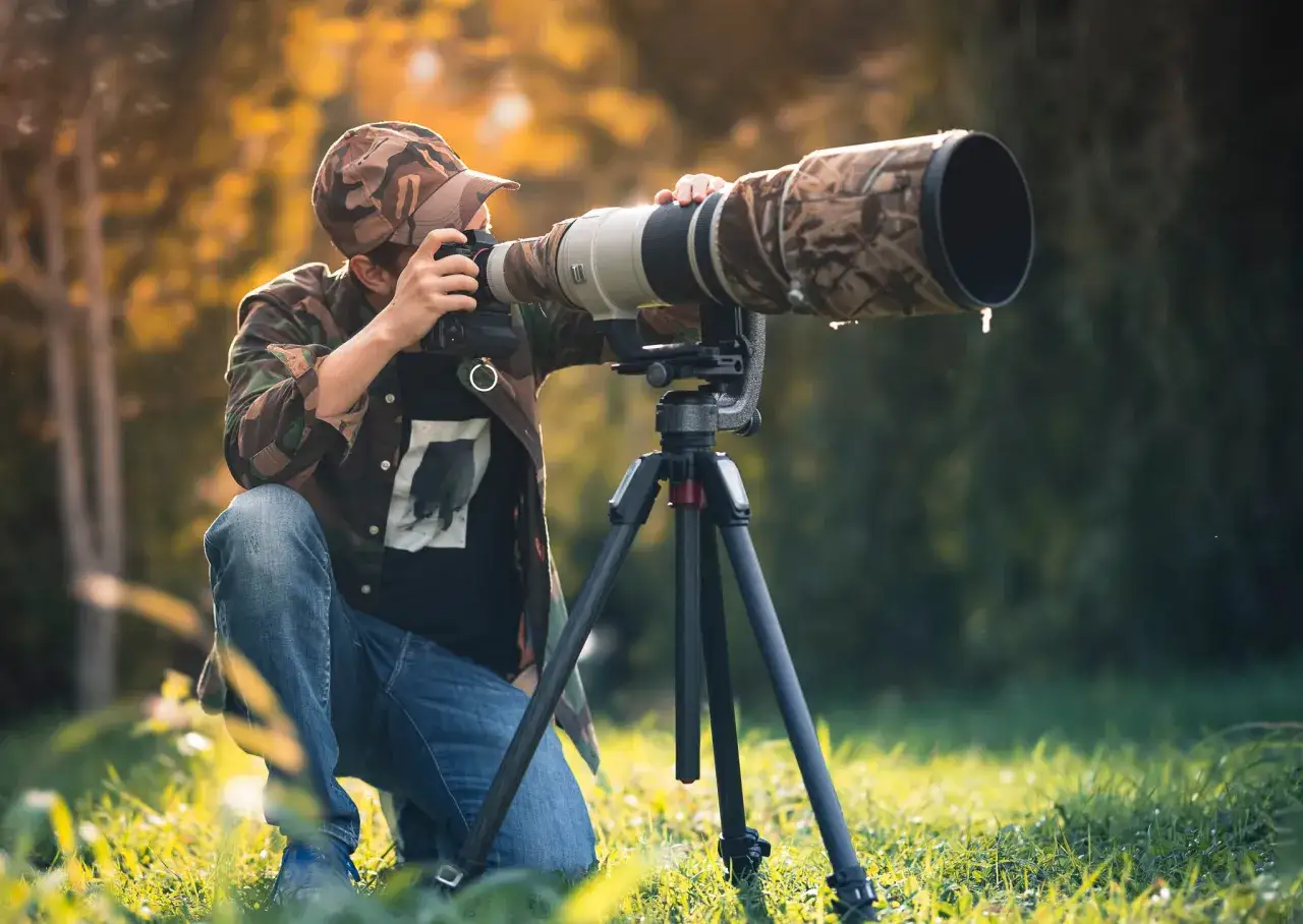 Fotografo con un obiettivo più costoso al mondo, mimetizzato tra la natura, pronto a catturare immagini uniche.