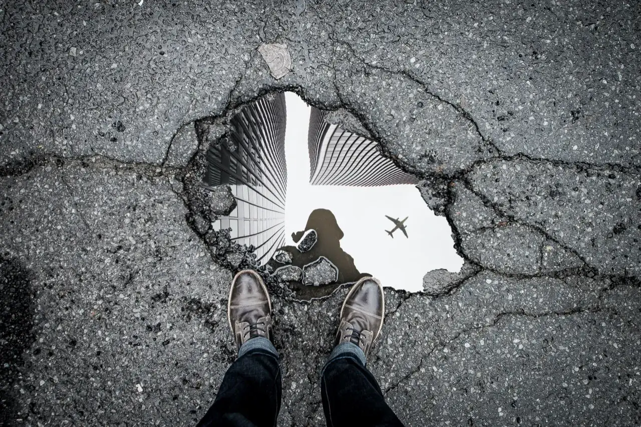 Riflesso di grattacieli e aereo in una pozzanghera: ottime idee per foto creative e inaspettate.